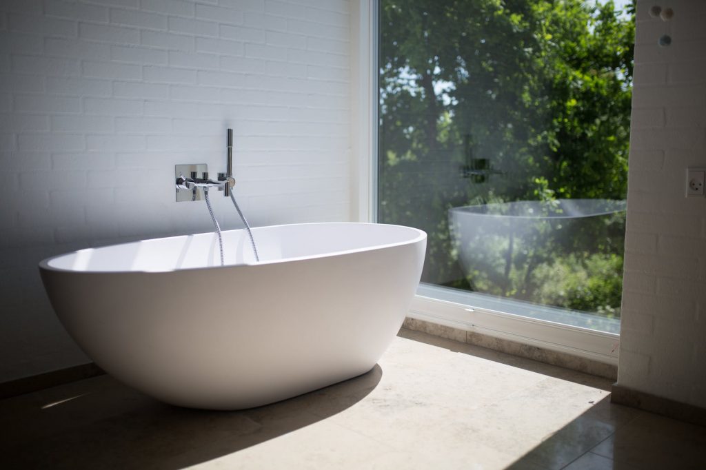 white ceramic bathtub beside clear glass wall