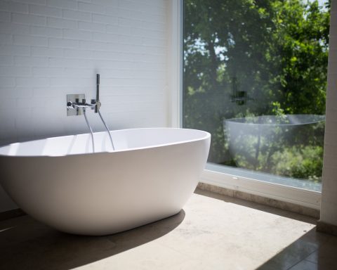 white ceramic bathtub beside clear glass wall